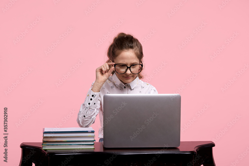 Focus online. A young girl with black-rimmed glasses is studying online. Focus online. A young girl with black-rimmed glasses is studying online.