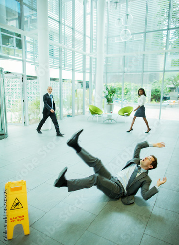 Foto Businessman slipping on floor of office building