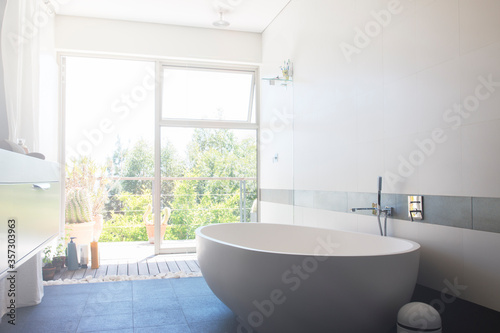 Modern bathroom with large white bathtub and patio door