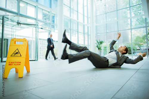 Businessman slipping on floor of office building