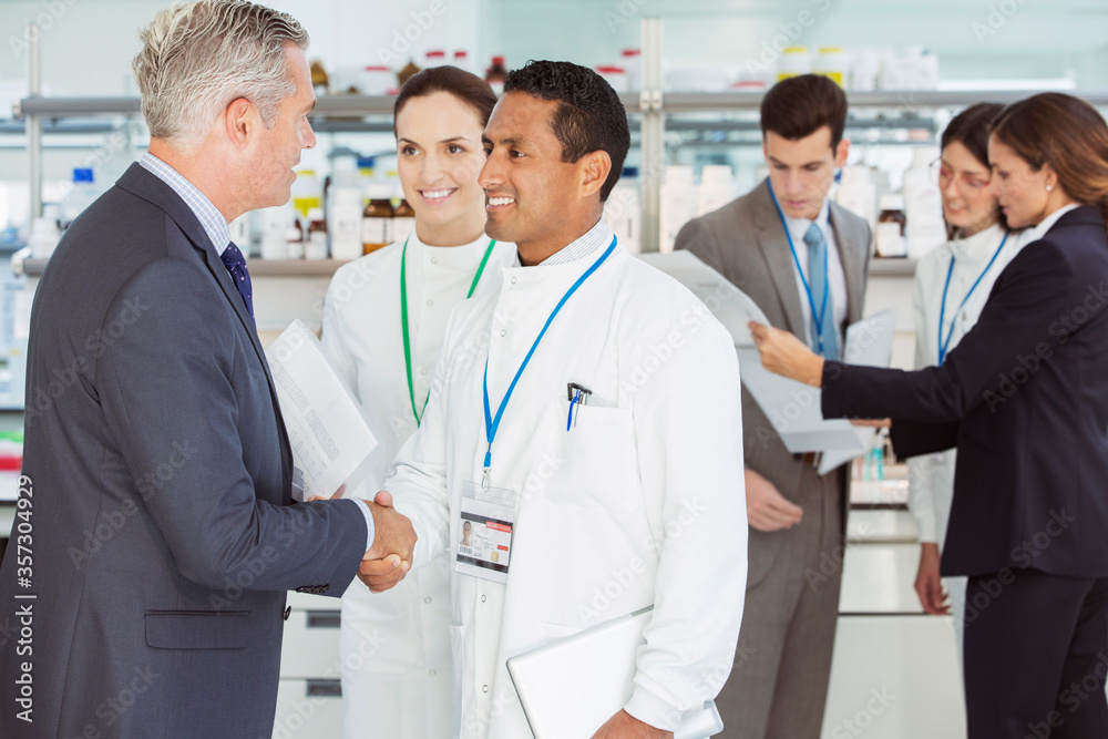Scientist and businessman shaking hands in laboratory Scientist and businessman shaking hands in laboratory