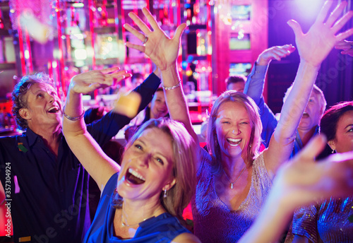 People raising hands and laughing in nightclub