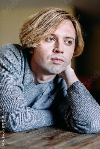 Handsome young man with blond hair looks thoughtfully to the side, dreams and goals in his thoughts, pensive and dreamy shot