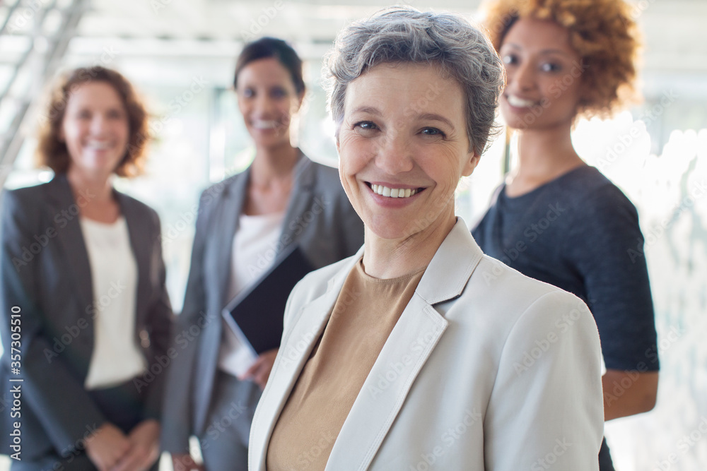Fototapeta premium Portrait of smiling mature businesswoman with office team 