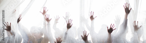 Silhouette of people raising hands behind transparent curtain