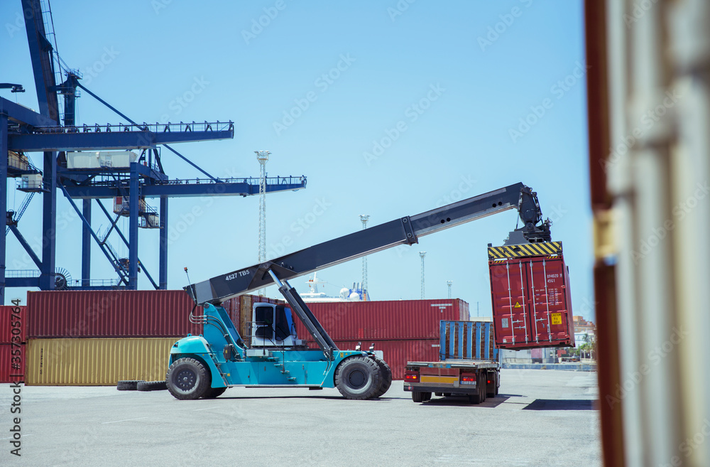 Fototapeta premium Crane lifting cargo container onto truck