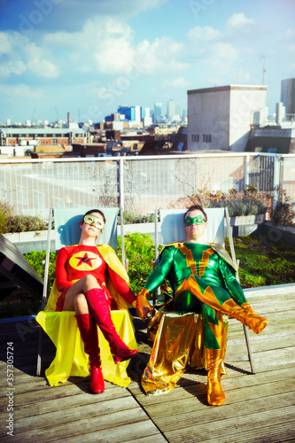 Superhero couple sitting on city rooftop