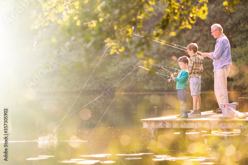 Grandfather and grandsons fishing at lake photo