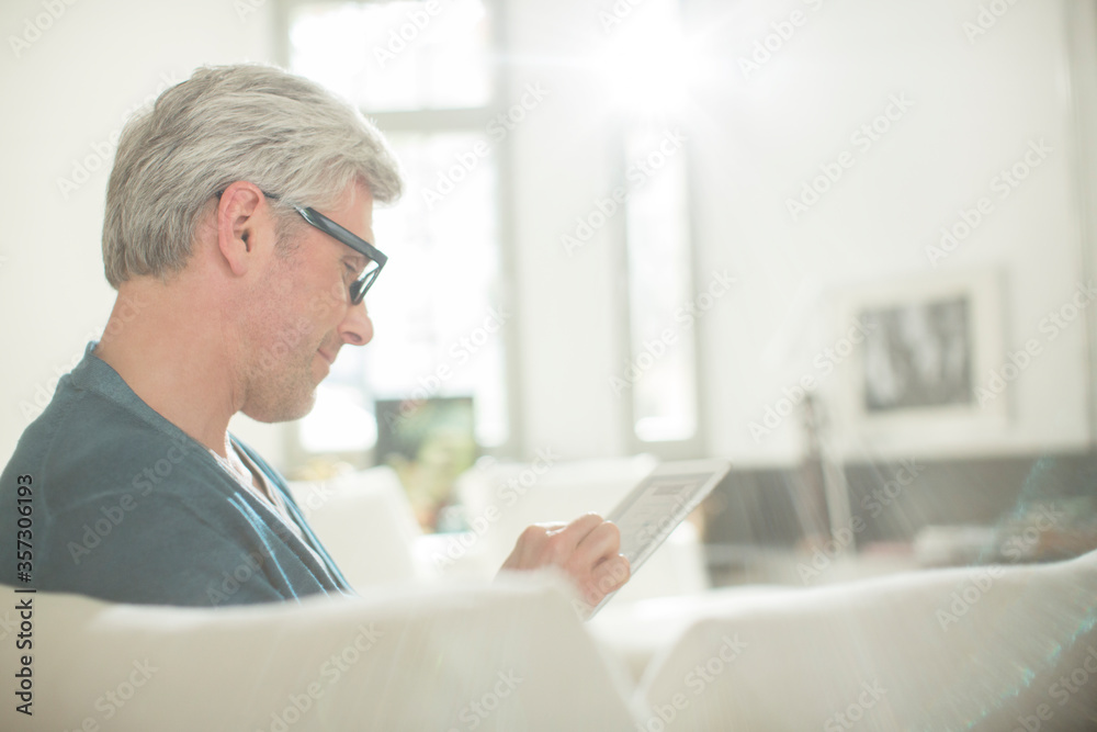 Older man using digital tablet on sofa