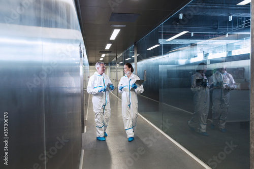 Scientists in clean suits walking in hallway