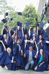 Group Portrait students in graduation gowns throwing mortarboards in the air