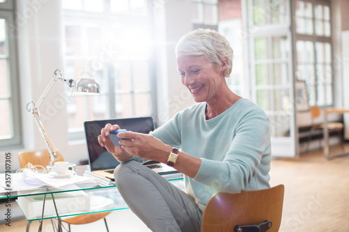Tableau sur toile Businesswoman using cell phone at home office desk