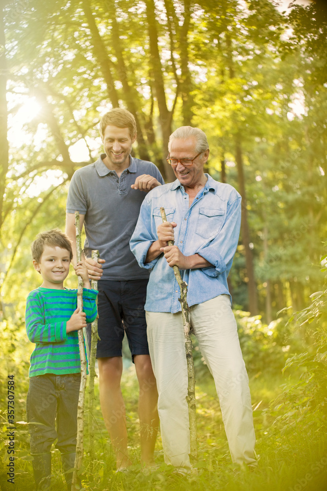 Boy, father and grandfather holding sticks in forest Boy, father and grandfather holding sticks in forest