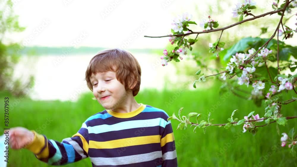 Happy kid boy taking off medical protective mask and breathing air, smelling flowers of apple, standing in blossoming apple tree. Cute child outdoors at sunset. End of quarantine, lockdown concept Happy kid boy taking off medical protective mask and breathing air, smelling flowers of apple, standing in blossoming apple tree. Cute child outdoors at sunset. End of quarantine, lockdown concept
