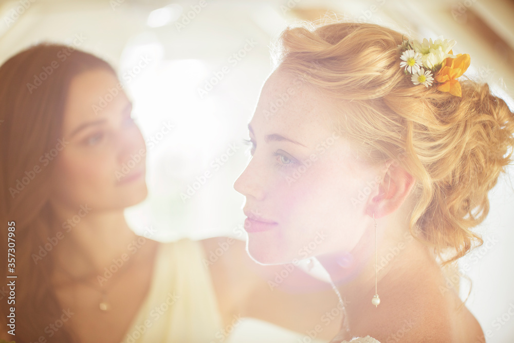 Portrait of bride with bridesmaid in background in domestic room