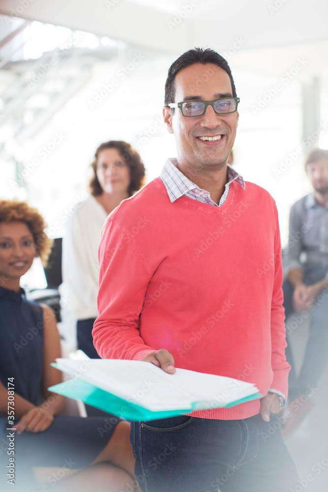 Fototapeta premium Portrait smiling businessman wearing glasses pink sweatshirt holding documents, office team 
