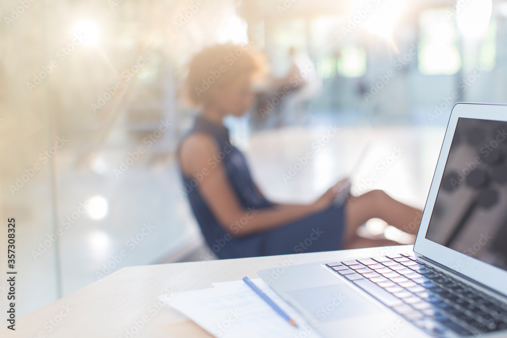 Open laptop on desk, woman in background Open laptop on desk, woman in background