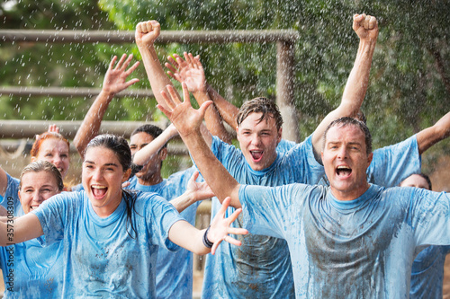 Enthusiastic team cheering in rain on boot camp obstacle course photo