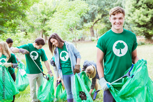 Portrait of smiling environmentalist volunteer picking up trash photo