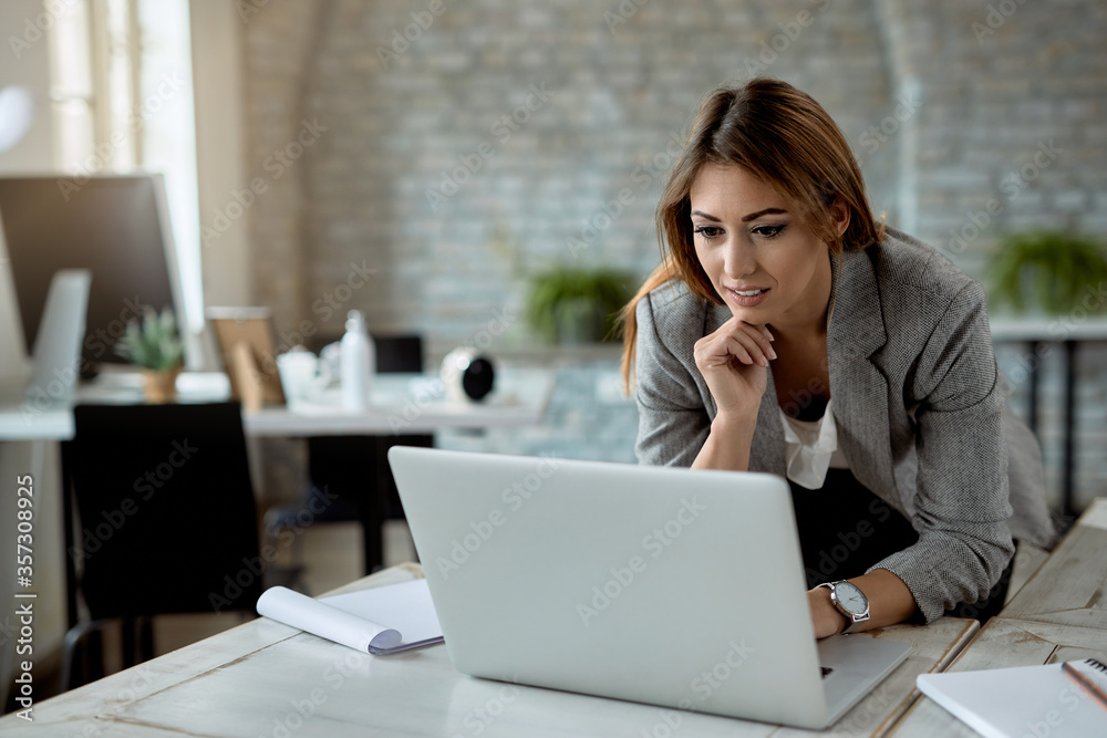 Female entrepreneur reading an e-mail on laptop in the office. Female entrepreneur reading an e-mail on laptop in the office.