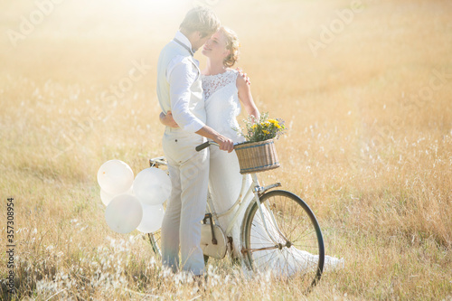 Young couple with bike kissing in meadow