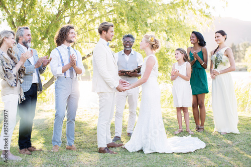 Young couple and guests during wedding ceremony in domestic garden