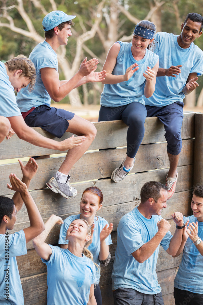 © Sam Edwards/KOTO - Team clapping and celebrating at wall on boot camp obstacle course
