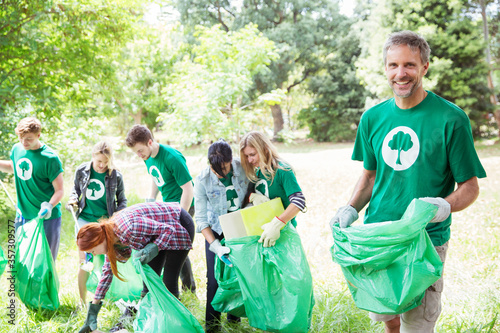 Portrait of smiling environmentalist volunteer picking up trash photo