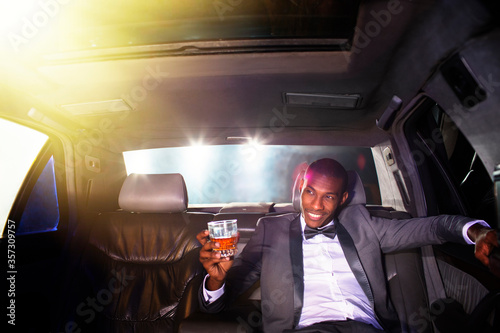 Fotografie, Obraz Celebrity drinking cocktail inside limousine outside event