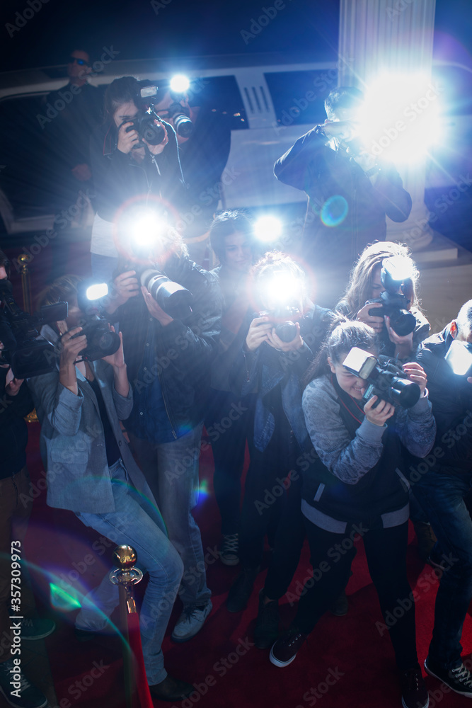 Naklejka premium Paparazzi photographers pointing cameras at red carpet event