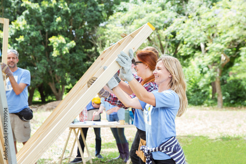 Volunteers lifting construction frame at construction site photo