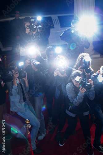 Paparazzi photographers pointing cameras at red carpet event