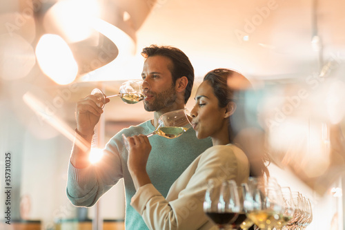 Couple wine tasting white wine in winery tasting room photo