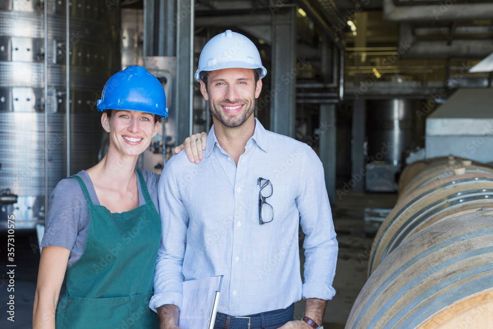 Portrait confident winery employees in hard hats in cellar Portrait confident winery employees in hard hats in cellar