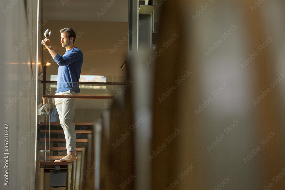 Man examining red wine on platform in winery cellar Man examining red wine on platform in winery cellar