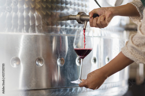 Vintner barrel tasting red wine from stainless steel vat