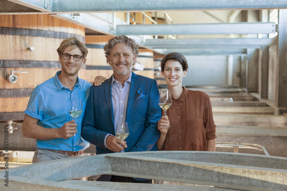 Portrait smiling vintners with white wine in winery cellar Portrait smiling vintners with white wine in winery cellar