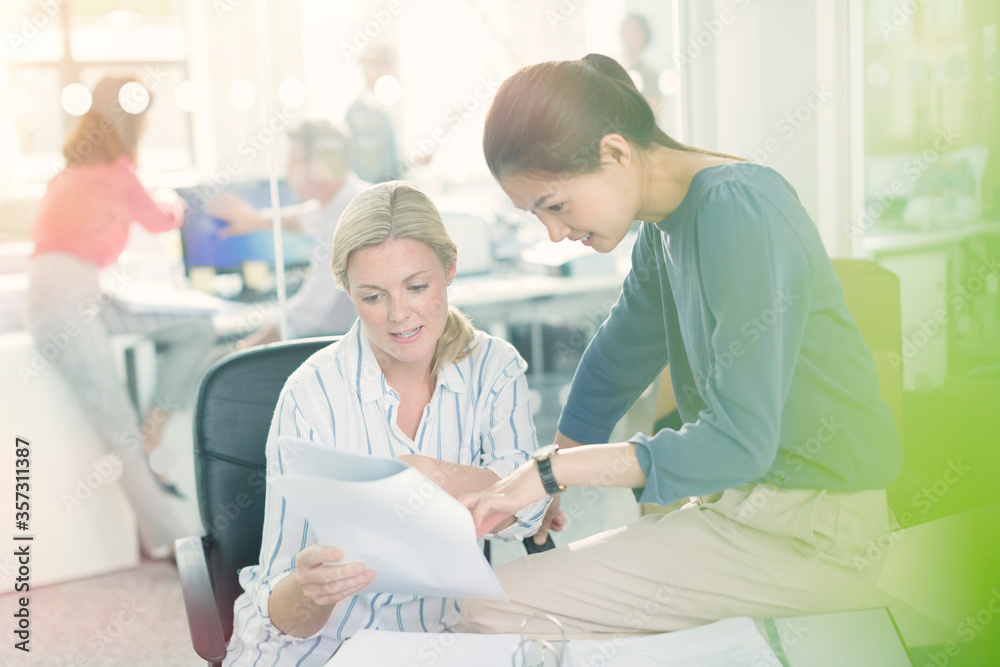 Obraz premium Businesswomen discussing paperwork in office