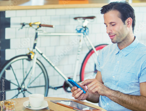 Man texting with cell phone near bicycle in cafe