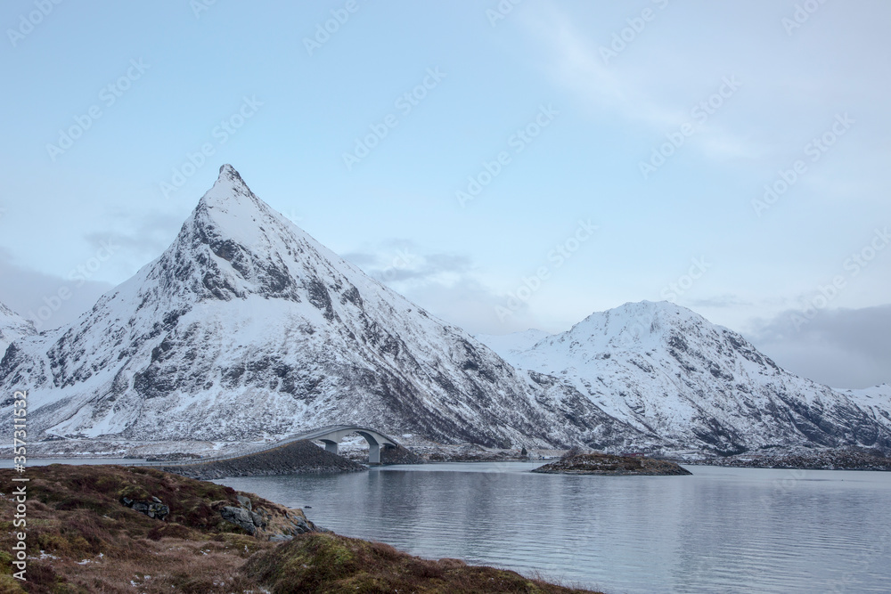 Snow covered mountains along cold lake, Lofoten Islands, Norway