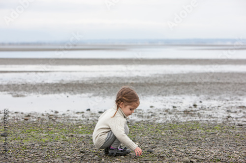 Girl picking up pebbles on beach
