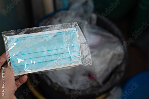 A hand holding used medical face mask stored in plastic  bag.Used disposable face mask in plastic bag. Safe way to throw away used face mask.Prevention for flu and virus covid-19