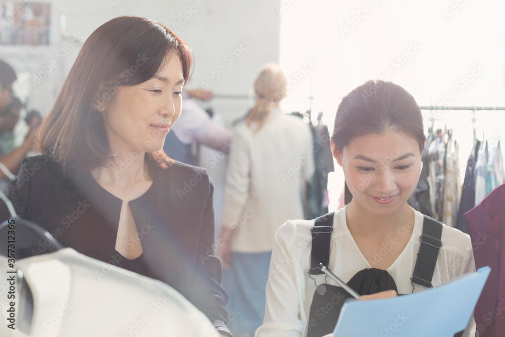 Fashion designer watching assistant taking notes Fashion designer watching assistant taking notes