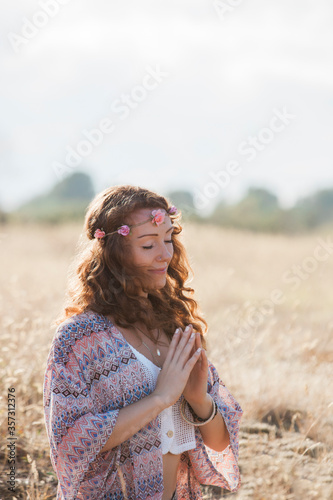 Serene boho woman meditating hands at heart center in sunny rural field