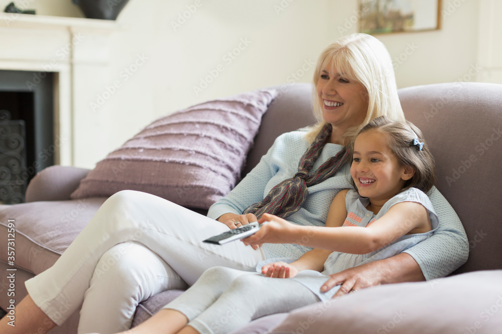 Grandmother and granddaughter watching TV on living room sofa Grandmother and granddaughter watching TV on living room sofa