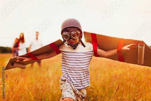 Photos Boy with wings in aviator cap and flying goggles in field