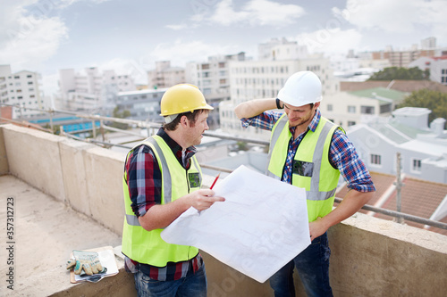 Construction worker engineer reviewing blueprints at highrise construction site