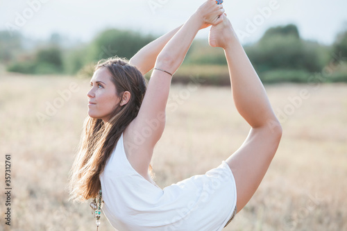 Boho woman in king dancer yoga pose in rural field