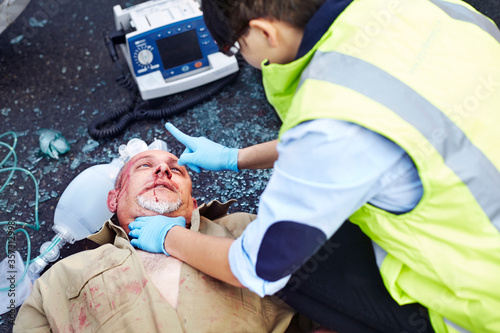 Rescue worker tending to car accident victim in road