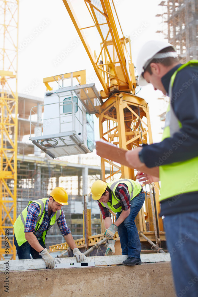 Photography Construction workers using level tool below crane at construction site
